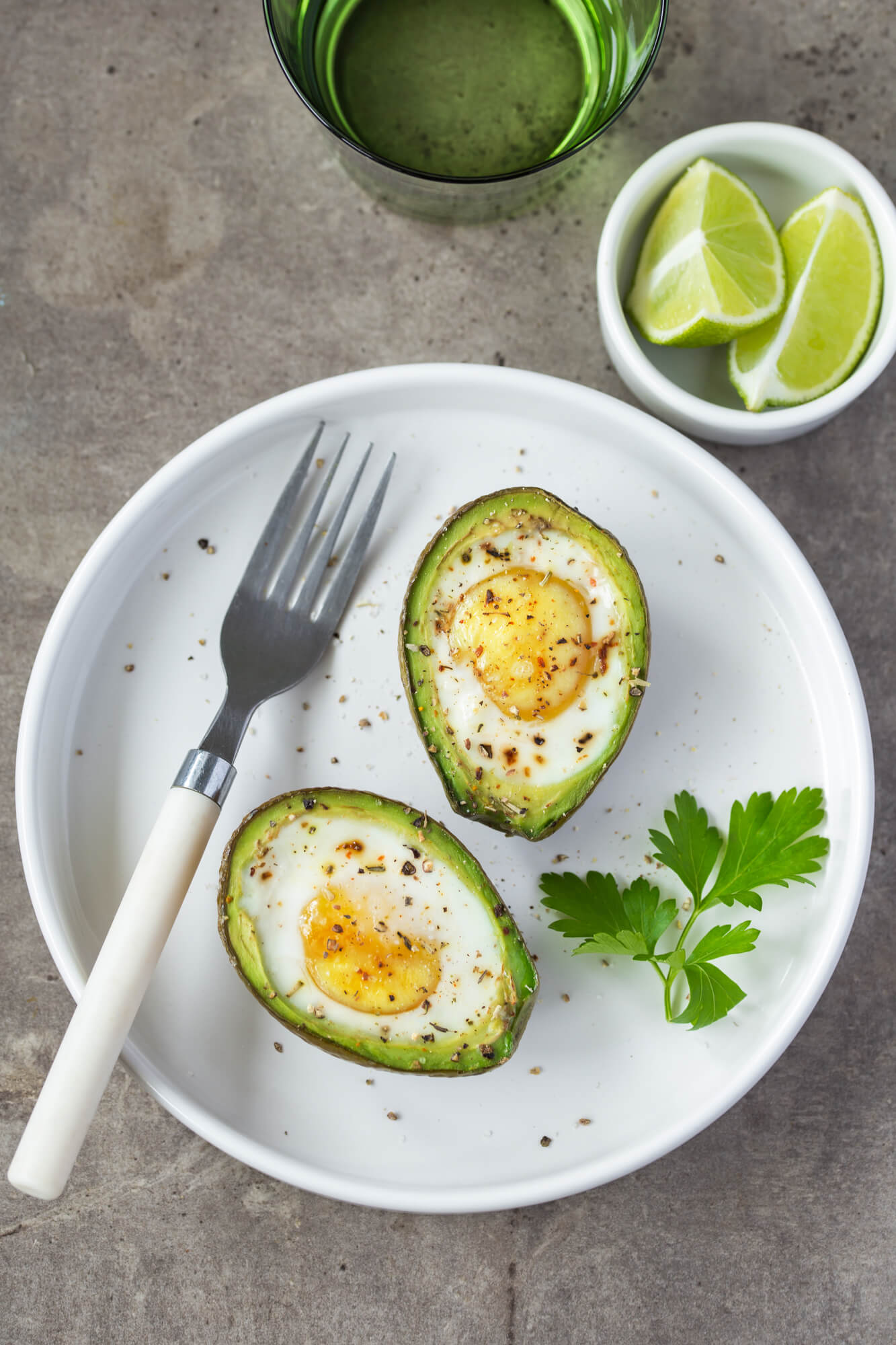 Avocado baked eggs with tomatoes and cilantro.