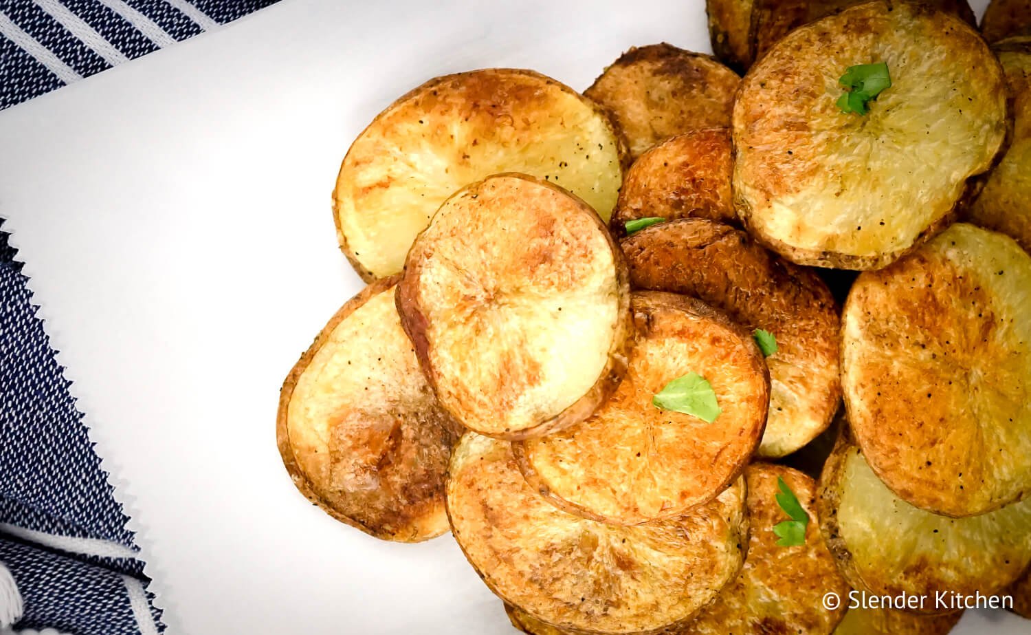 Healthy potato chips on parchment paper with parsley