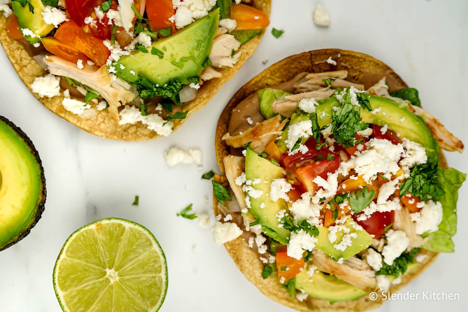 Chicken tostadas with all the toppings and a fresh avocado and lime.