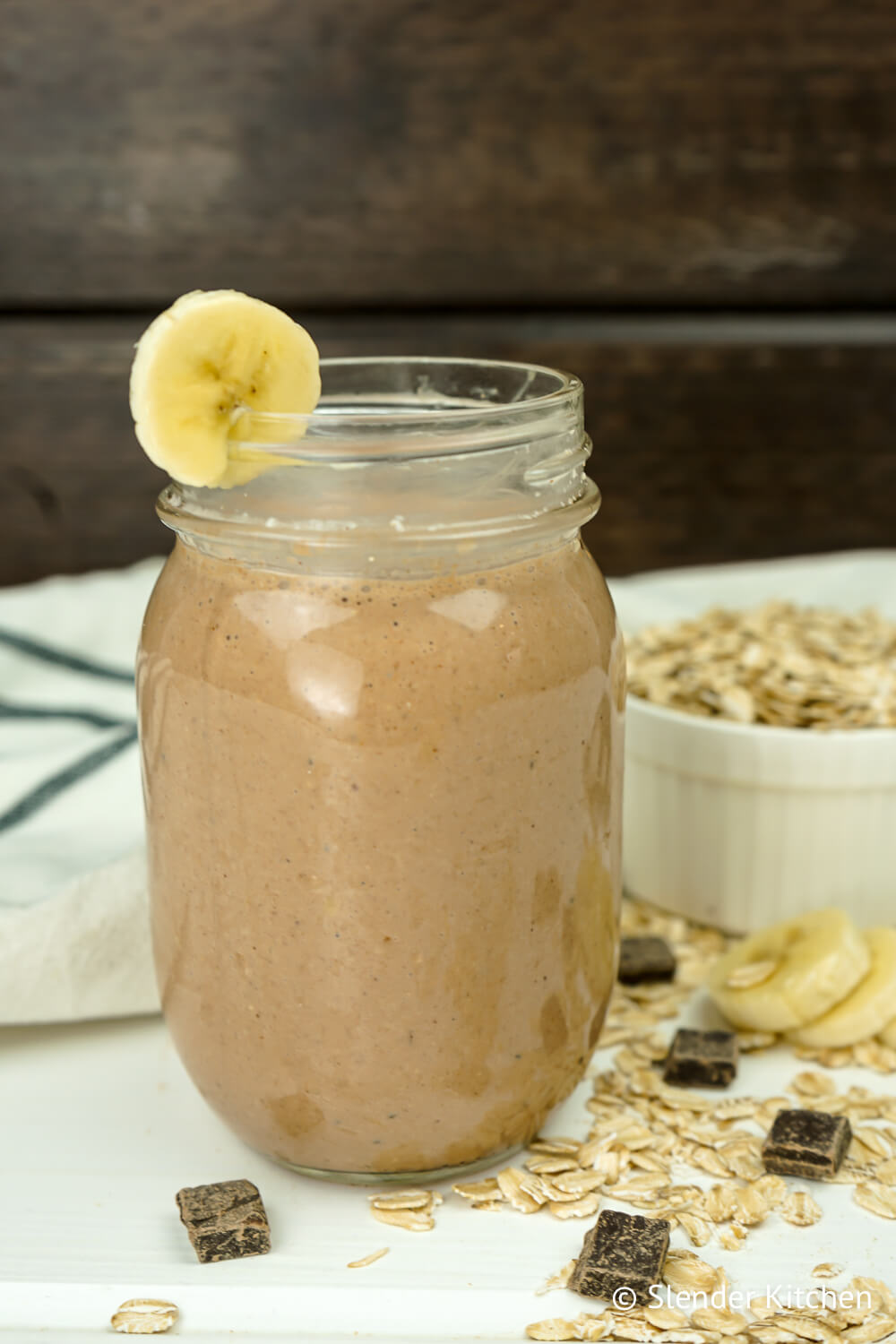 Chocolate banana smoothie in a mason jar with loose oats and chocolate.