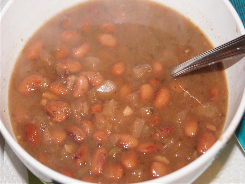 Pinto beans in broth in a white bowl.