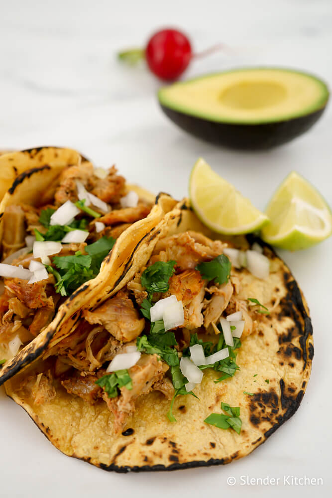 Slow Cooker Carnitas in corn tortillas with cilantro and onion.