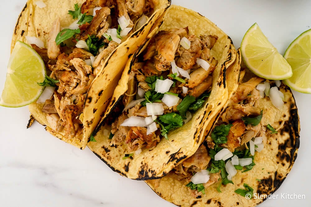 Easy carnitas in three tacos with onion, limes, and cilantro.