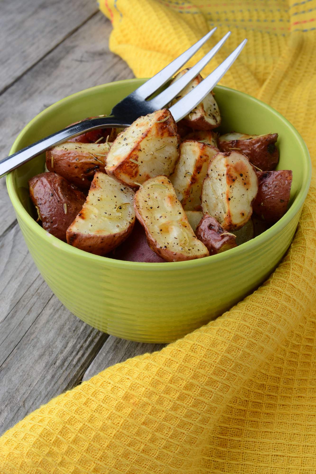 Grilled red potatoes in a bowl with a yellow napkin.