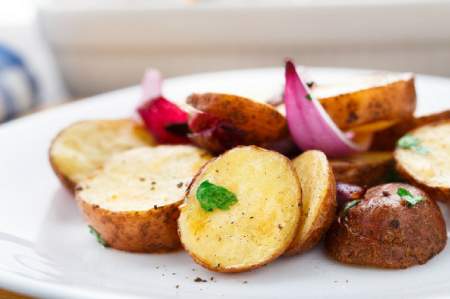 Grilled potatoes with onions on a white plate.