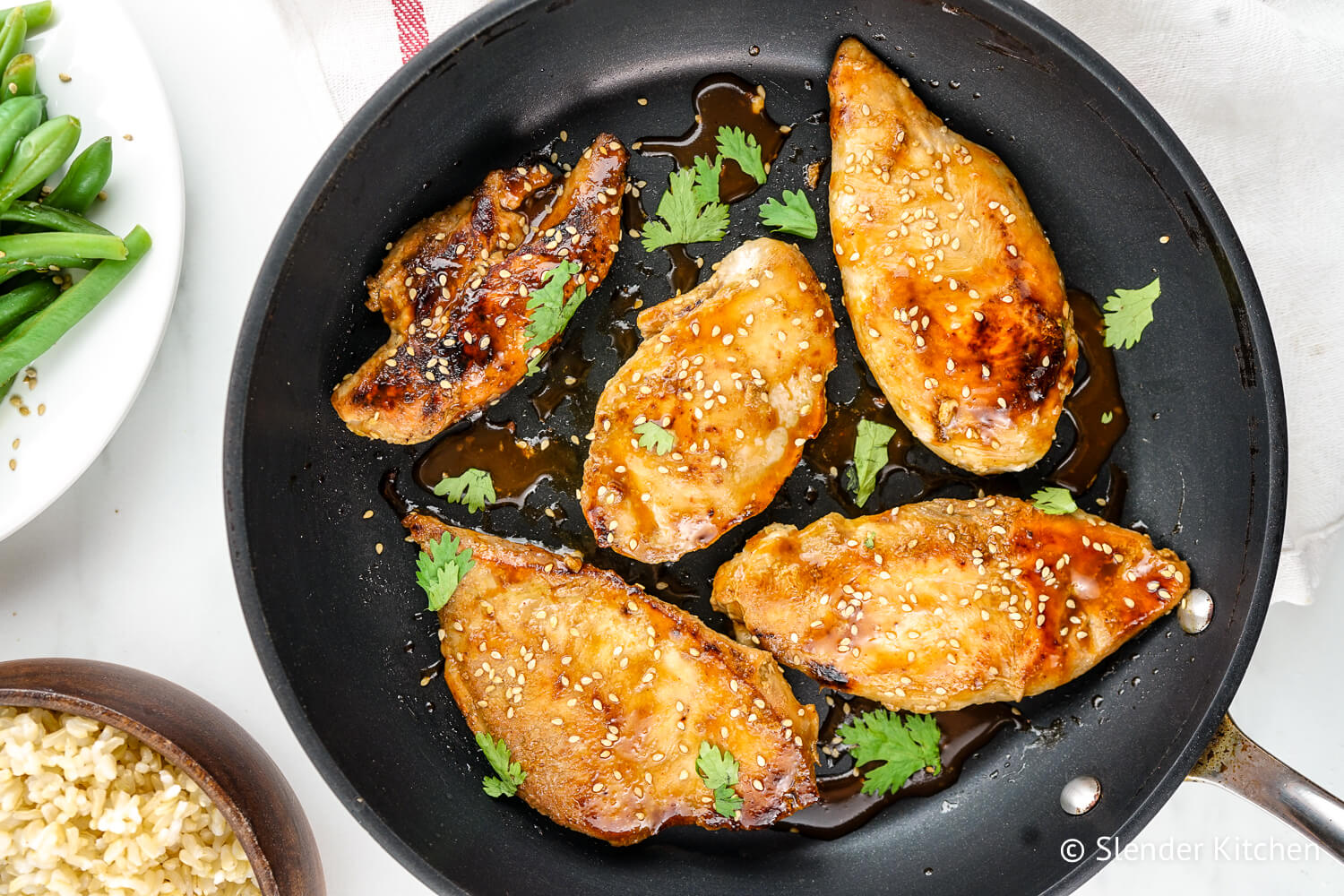 Honey soy chicken in a pan with green beans and rice on the side.