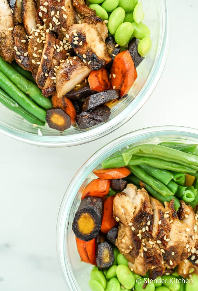 Honey soy glazed chicken in a glass bowl with carrots, edamame, and green beans.