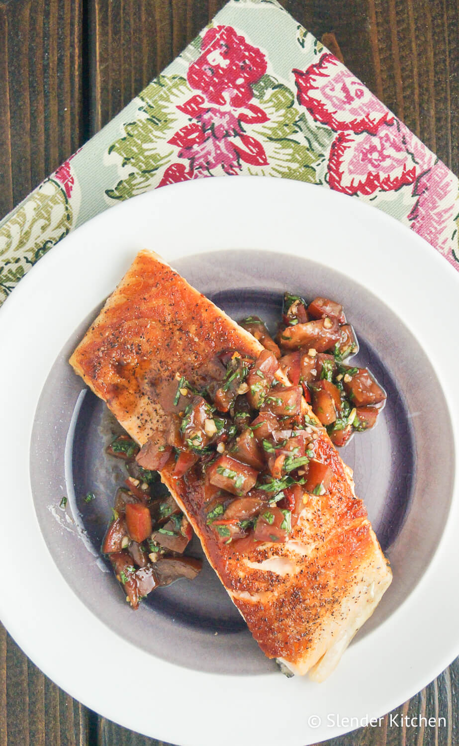 Italian salmon with tomato basil salsa on a white plate with a flowered napkin.