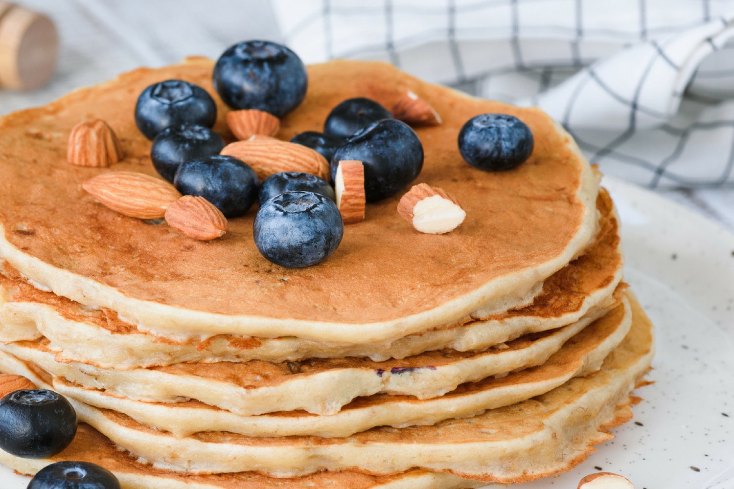 Low carb almond flour pancakes with blueberries and almonds on a white plate.