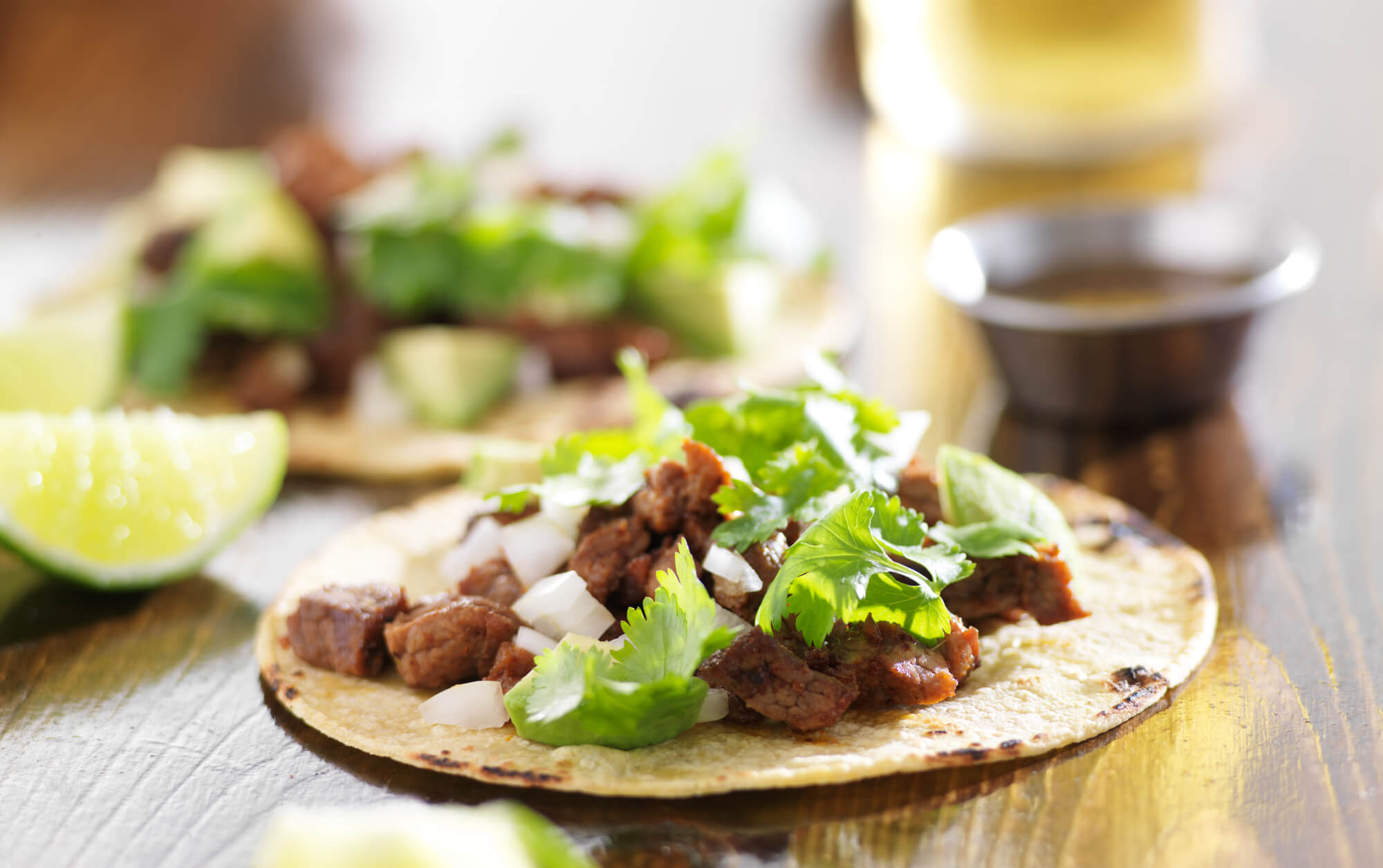 Close up of a steak taco on a corn tortilla with onion and cilantro.