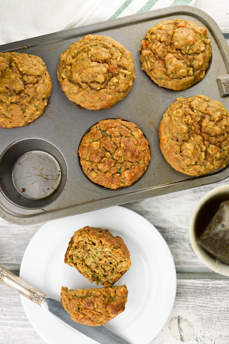 Zucchini and carrot muffins on a plate with a knife.