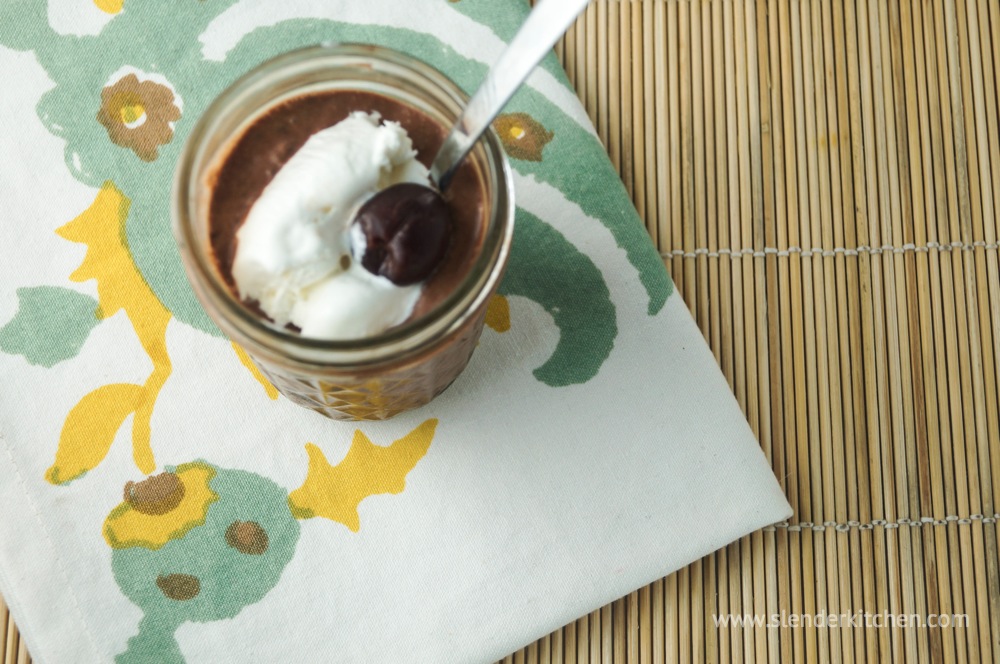 A chocolate chia seed pudding with whipped cream on a floral napkin.