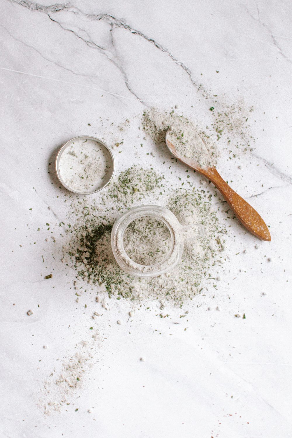 Jar of homemade ranch seasoning with a wooden spoon and dried herbs.