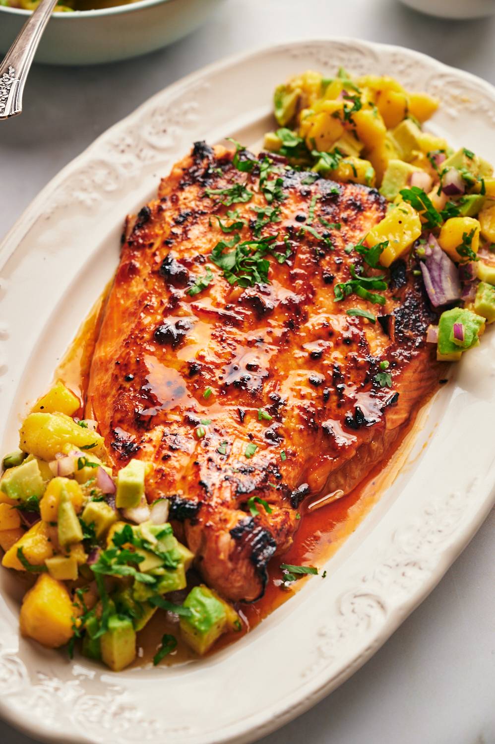 Salmon with mango avocado salsa served on a plate with honey chipotle glaze.