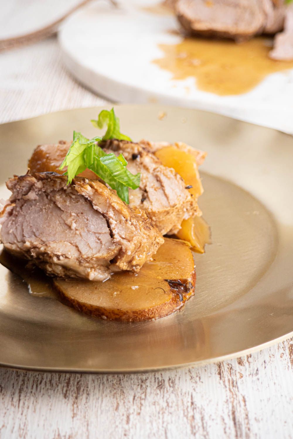 Balsamic pork tenderloin with pears, honey, and soy sauce sliced on a plate with cooked pear.