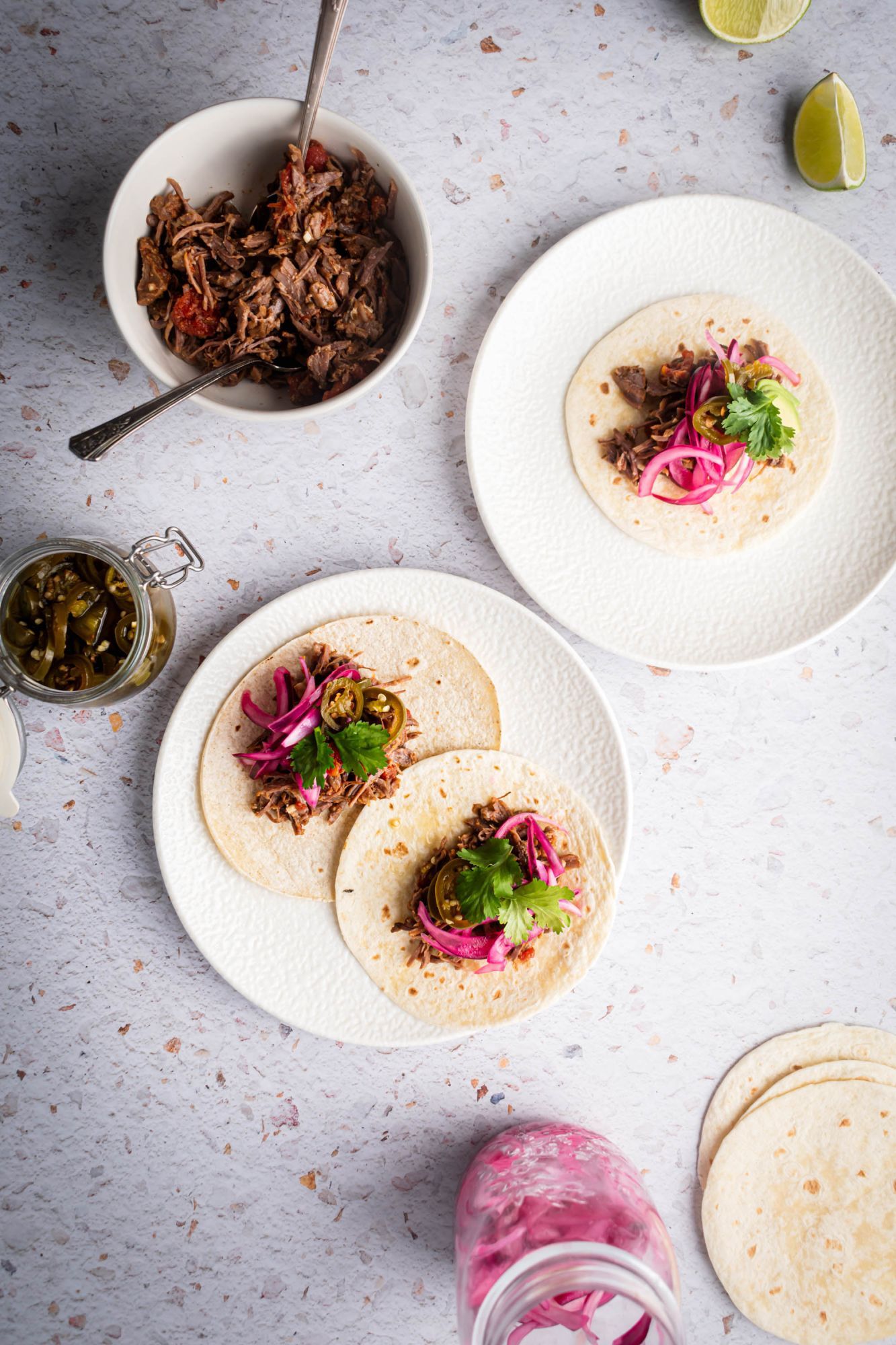 Mexican shredded beef tacos served on flour tortillas with pickled red onions, jalapenos, and cilantro.