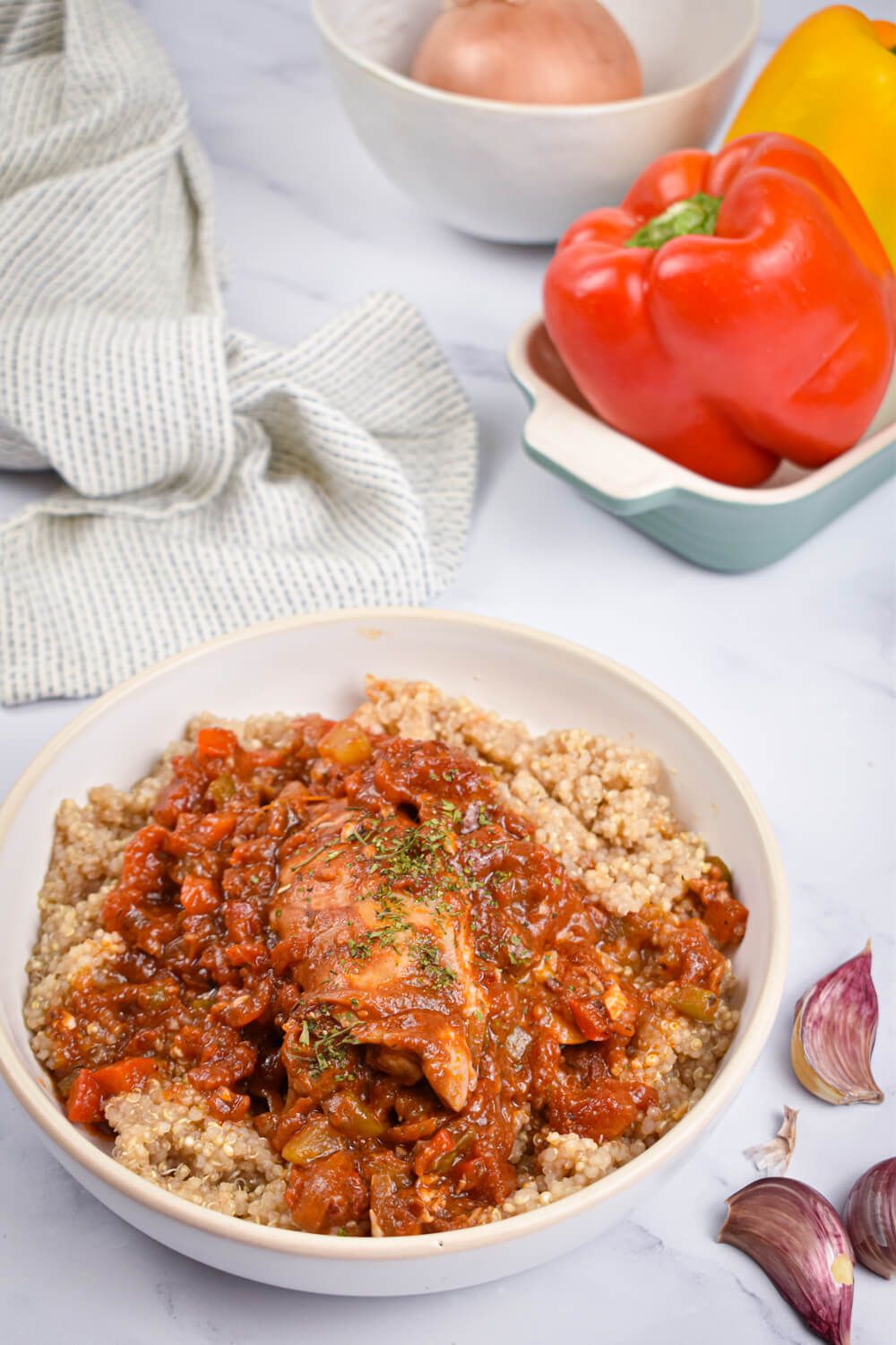 Chicken cacciatore with mushrooms, peppers, and chicken in a bowl with quinoa.