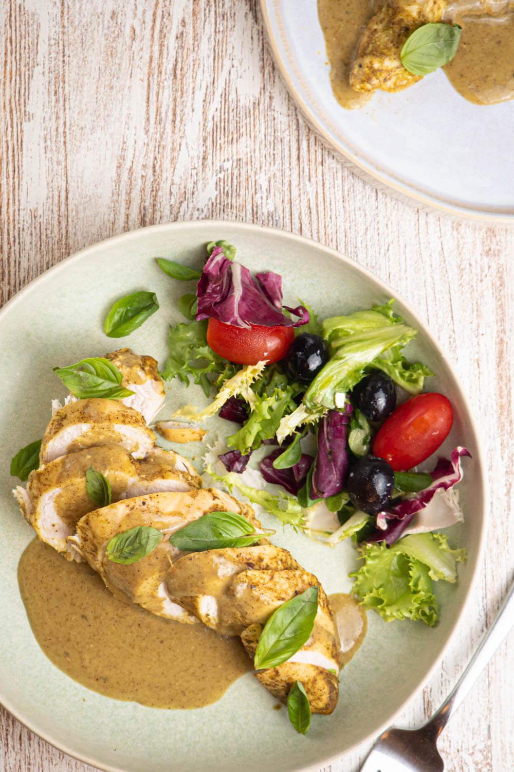 Coconut basil chicken breast cut into sliced with a creamy sauce and salad.