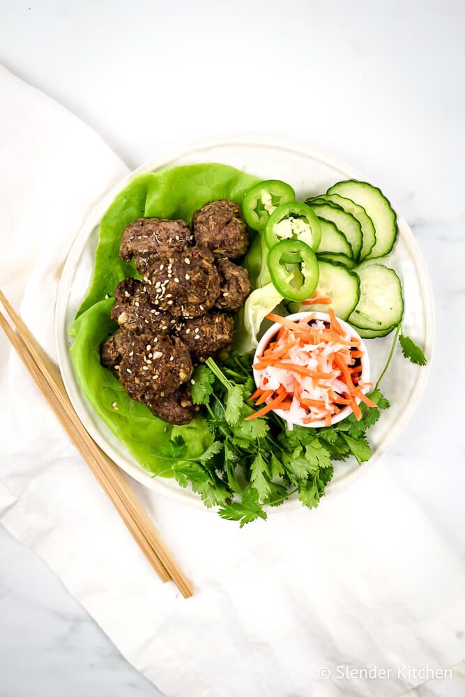 Asian meatballs with soy sauce, cucumbers, carrots, Daikon, and sesame seeds on lettuce wraps.