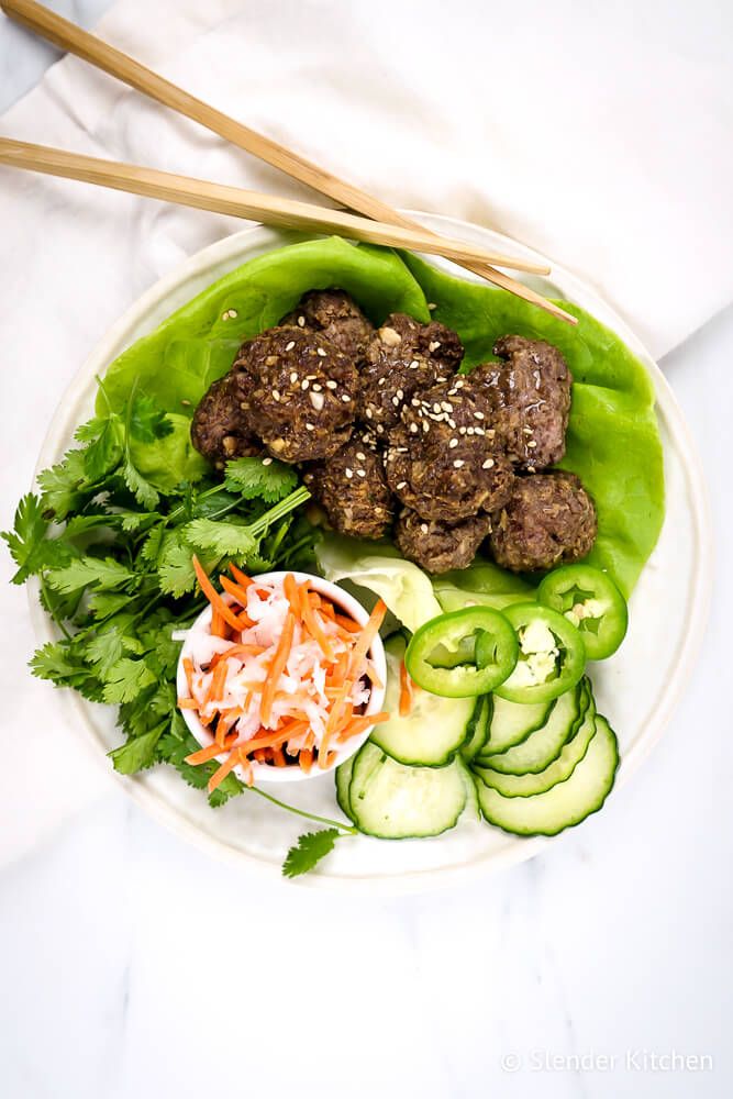Asian beef meatballs on lettuce leaves with chopsticks and a white napkin.