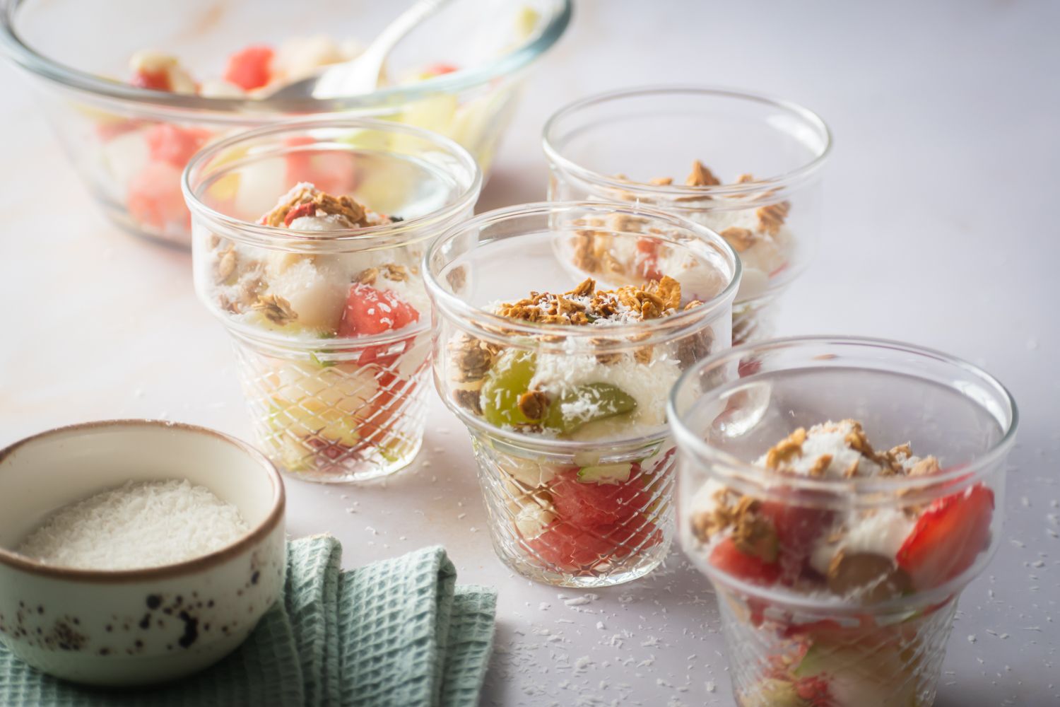 Mexican fruit salad bionico with watermelon, strawberries, grapes, and apples in a condensed milk sauce in glass cups.
