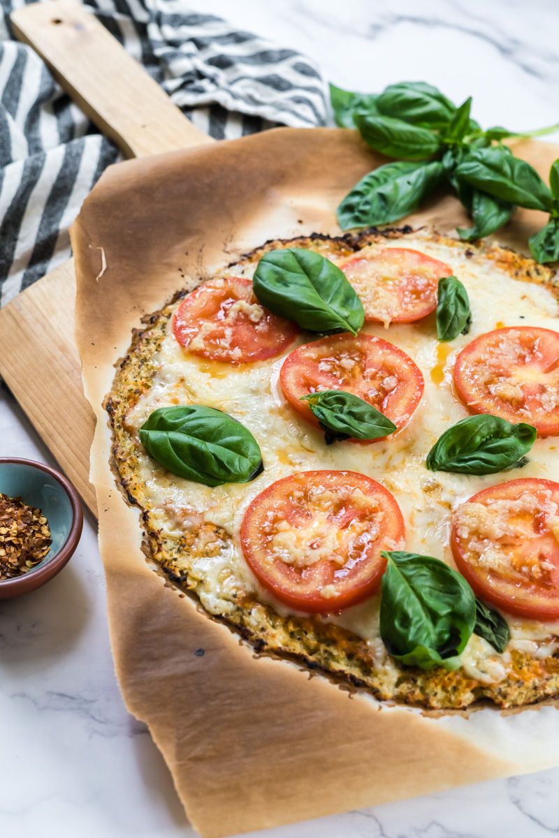 Cauliflower pizza dough cooked until crispy and topped with mozzarella, tomatoes, and basil.