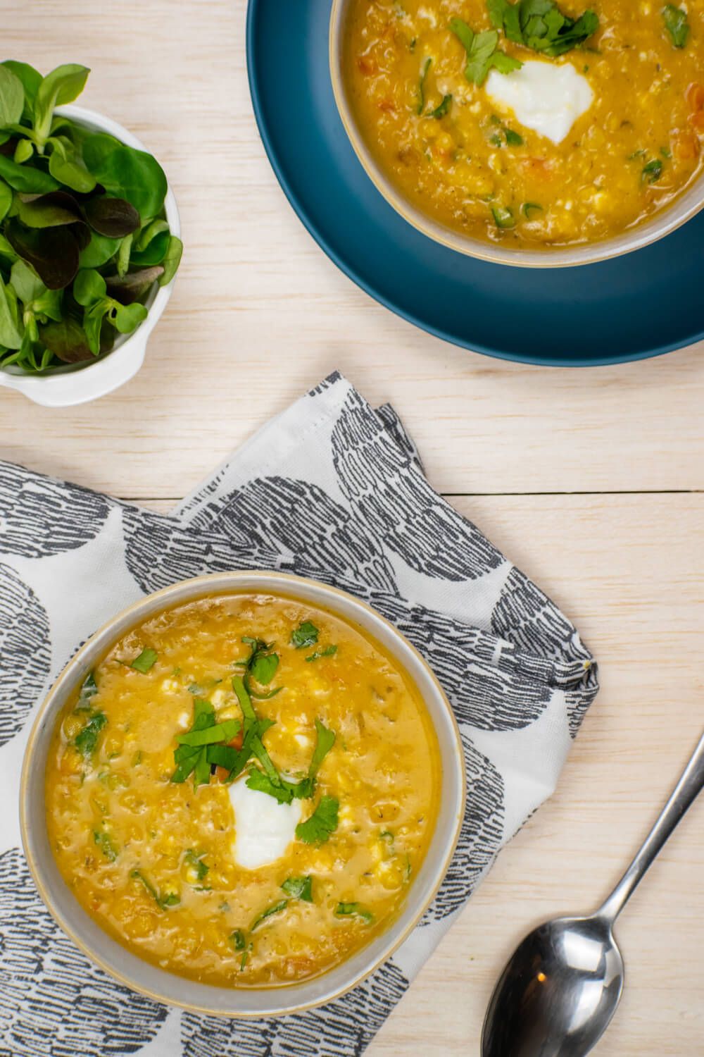 Red lentil soup with carrots and curry in a bowl with fresh herbs and yogurt.