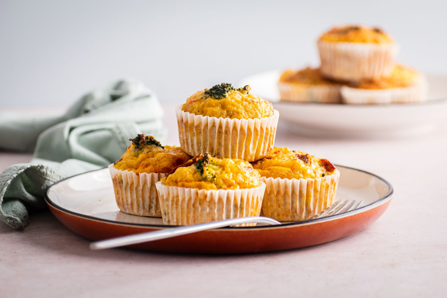 Baked quinoa and egg muffins cooked in a muffin tin with sundried tomatoes, cheese, and broccoli.