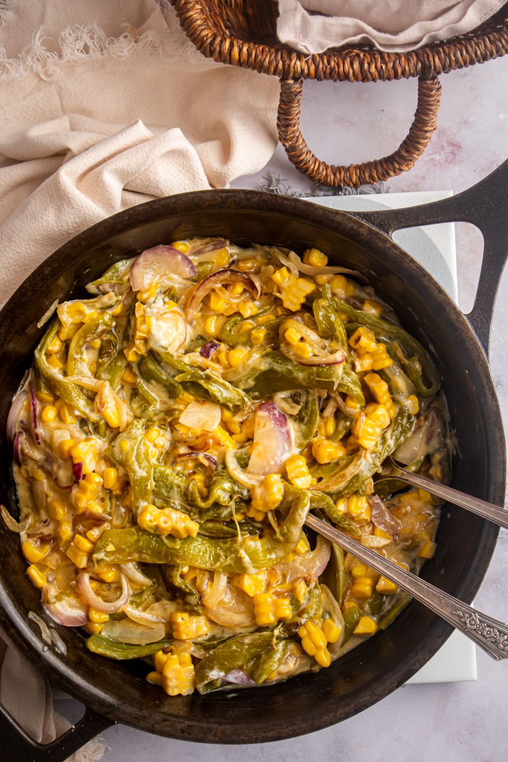 Skillet with rajas con queso including sautéed poblano peppers, corn, red onion, and creamy cheese sauce.