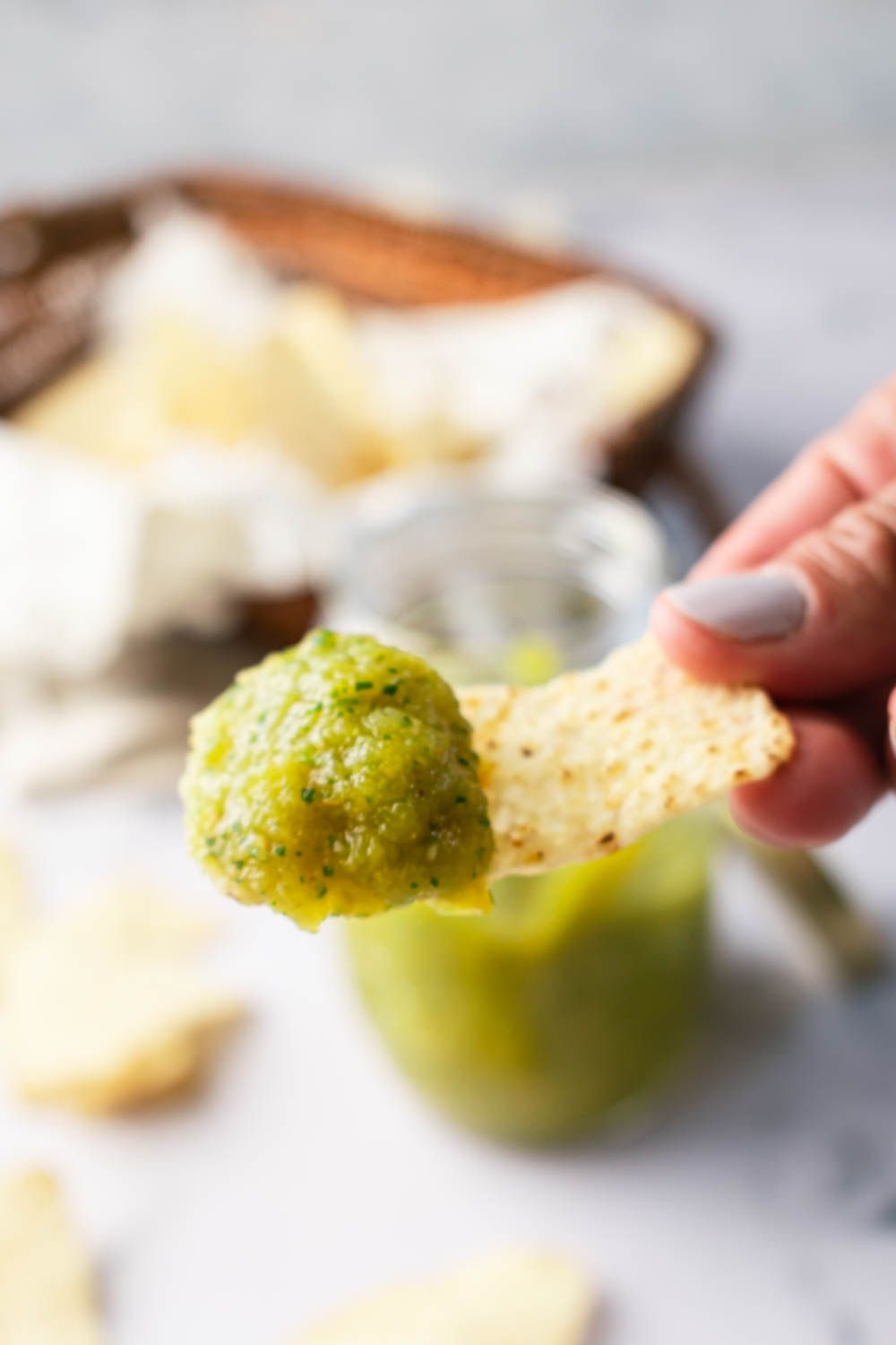 Green salsa verde with blended tomatillos and jalapeños on a tortilla chip.