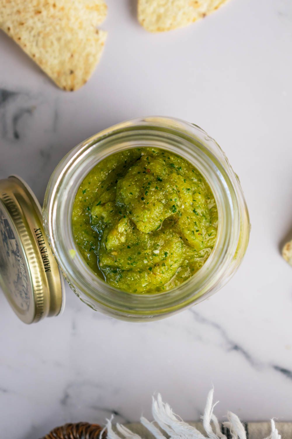 Mexican salsa verde with tomatillos, jalapenos, and cilantro blended in a jar with chips on the side.