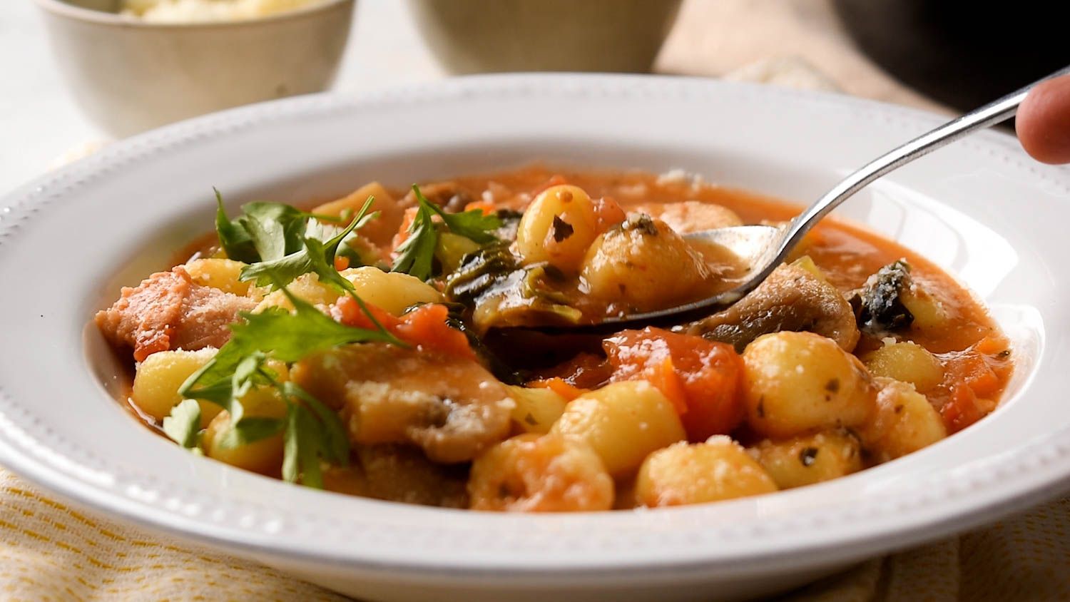 Chicken sausage and gnocchi soup in a bowl with mushrooms, tomatoes, potato gnocchi, and sausage.