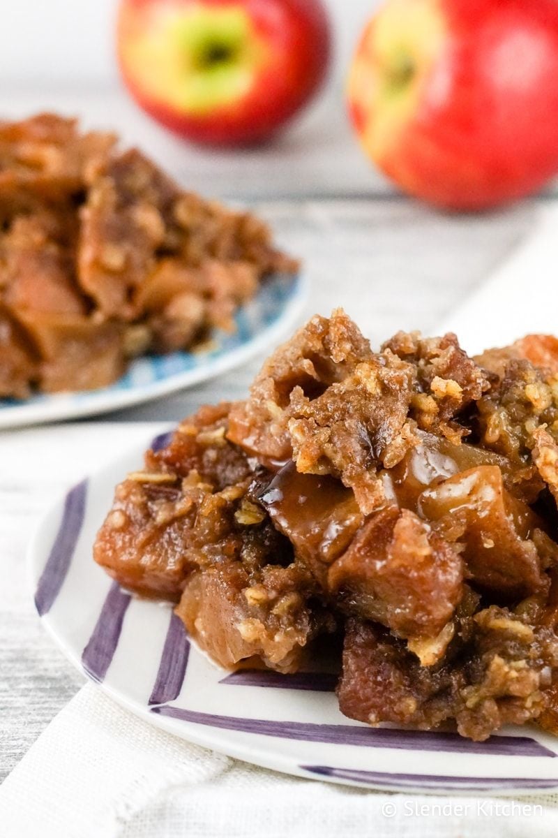 Slow Cooker Apple Crisp served on a plate with apples in the background.