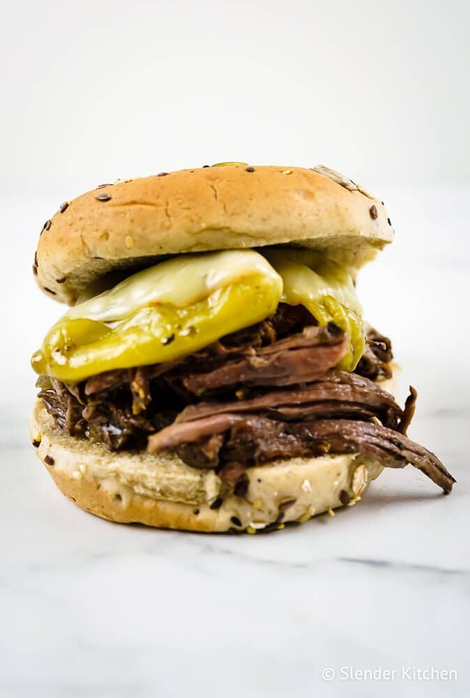 Shredded beef with pepperoncinis made in the slow cooker and served on a sandwich roll with melted cheese.
