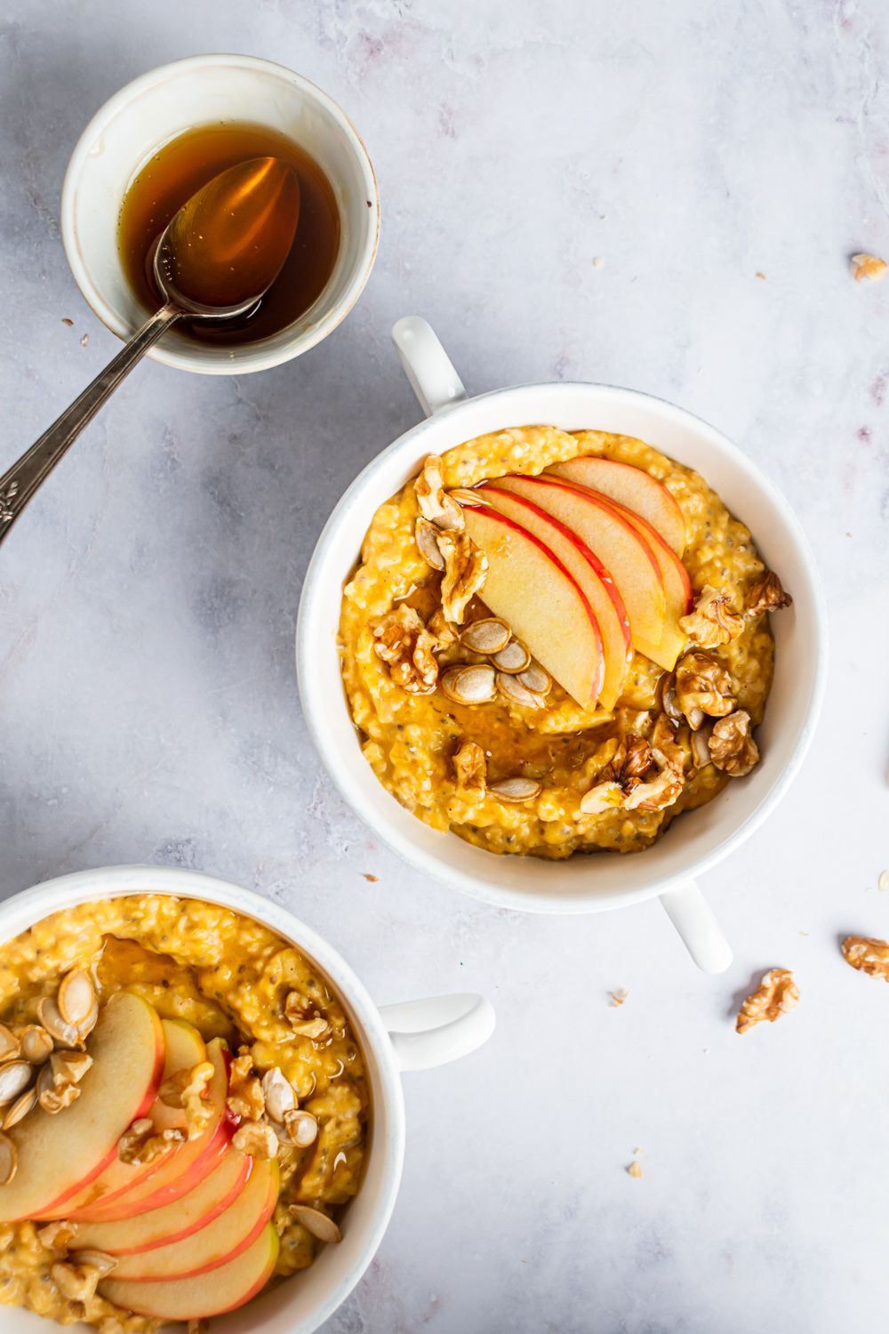 Pumpkin steel cut oatmeal with walnuts, pumpkin seeds, maple syrup, and slices apples.