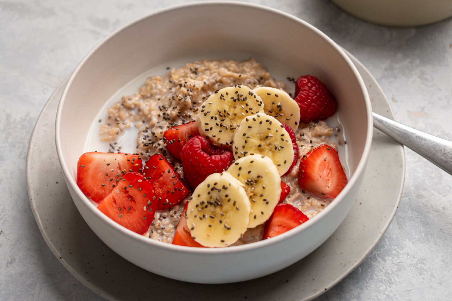 Steel cut oatmeal cooked in the slow cooker and served with milk, fresh berries, bananas, and chia seeds in a bowl.