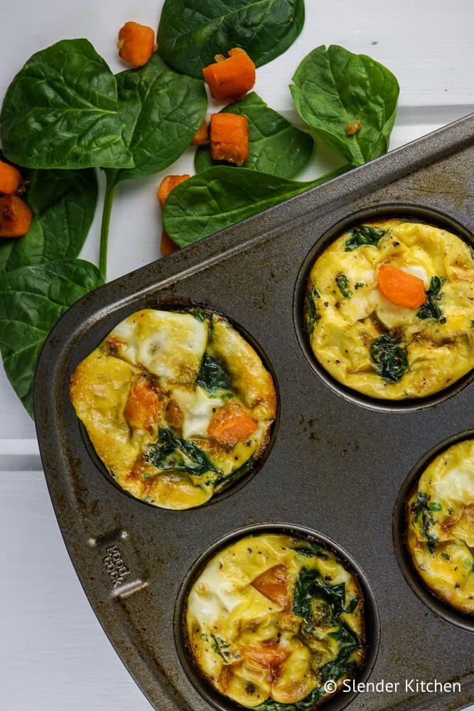 Egg muffins with sweet potatoes and spinach in a muffin tin with spinach and potatoes on the side.