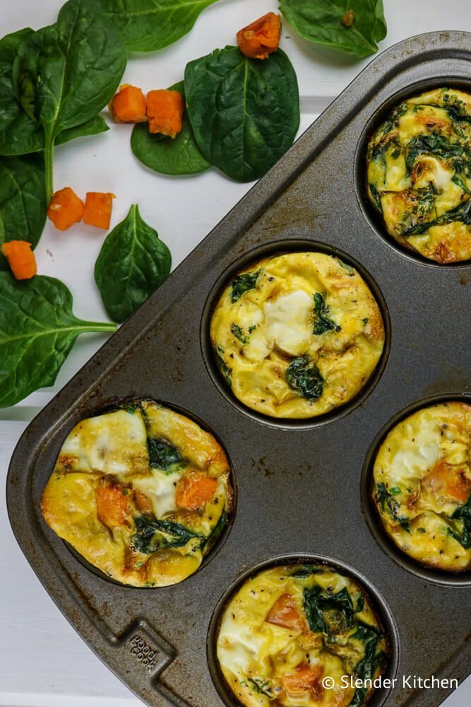 Sweet potato egg muffins with spinach in a muffin tin with vegetables on the side.