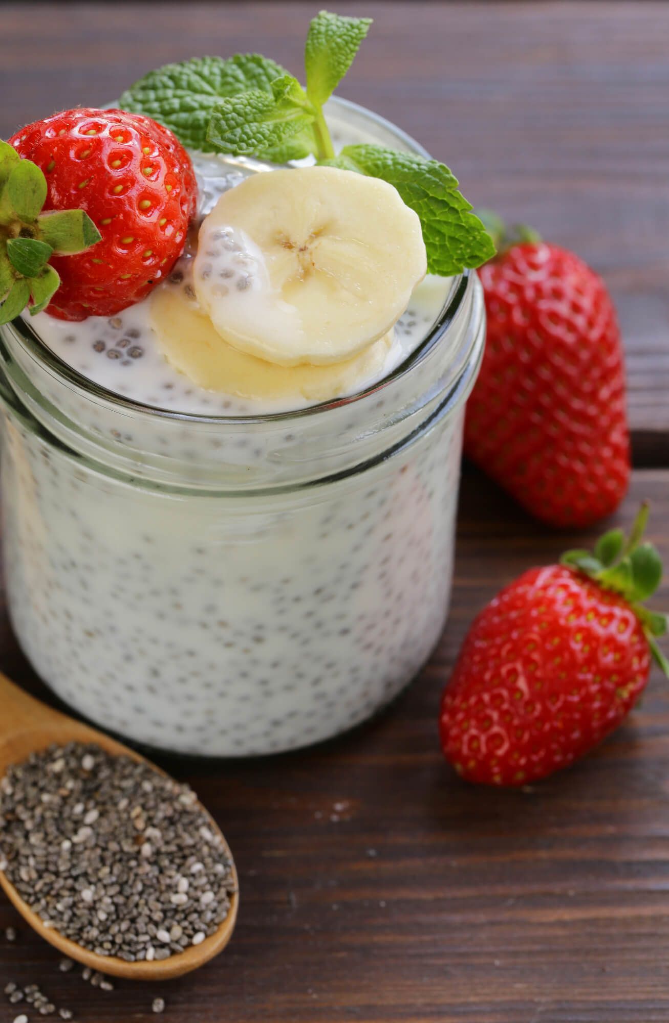 Yogurt chia seed pudding in a glass jar with a sliced banana and strawberry.