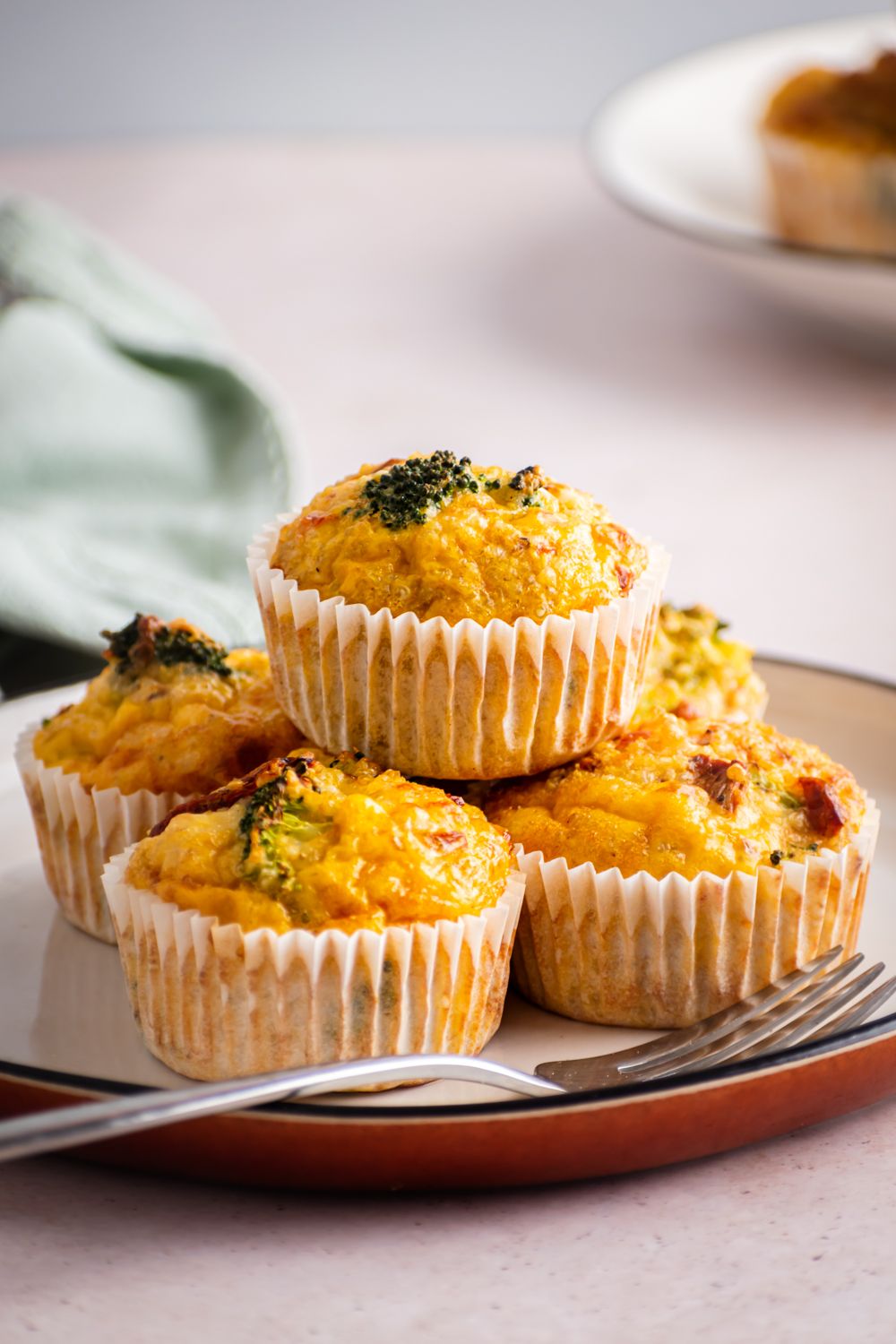 Breakfast egg muffins baked with quinoa, broccoli, tomatoes, and cheese on a plate with a blue napkin.