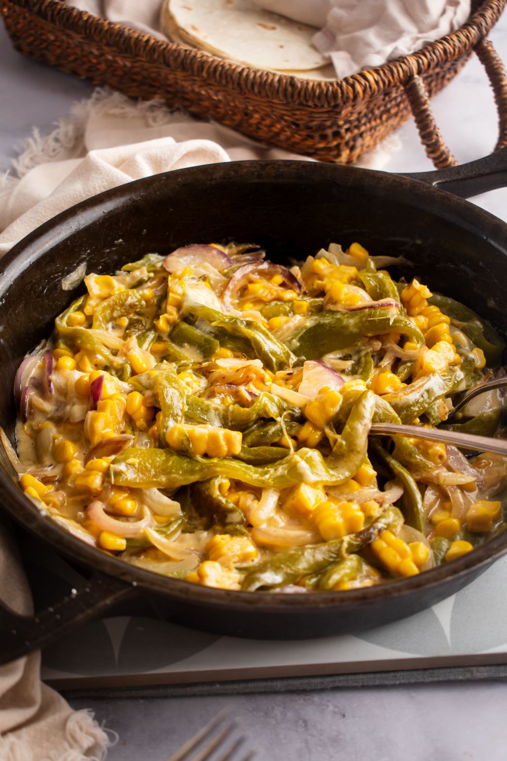 Poblano peppers cooked with onions and corn and served in a creamy cheese sauce in a cast iron skillet.