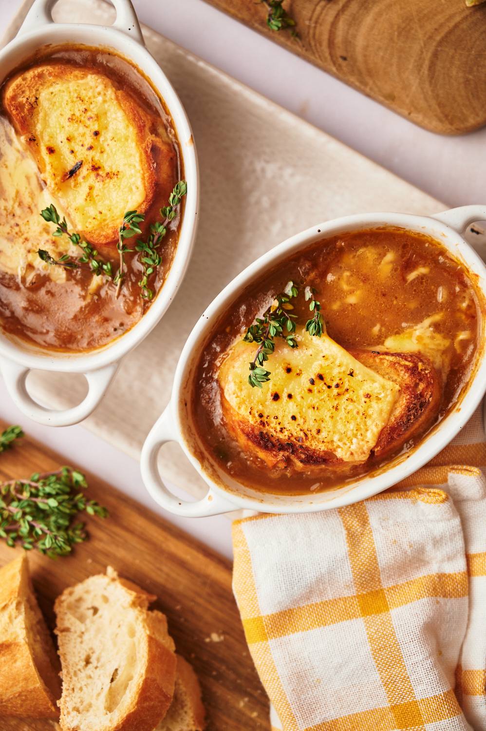 Crockpot French onion soup in two bowls with toasted bread, melted cheese, and fresh thyme.