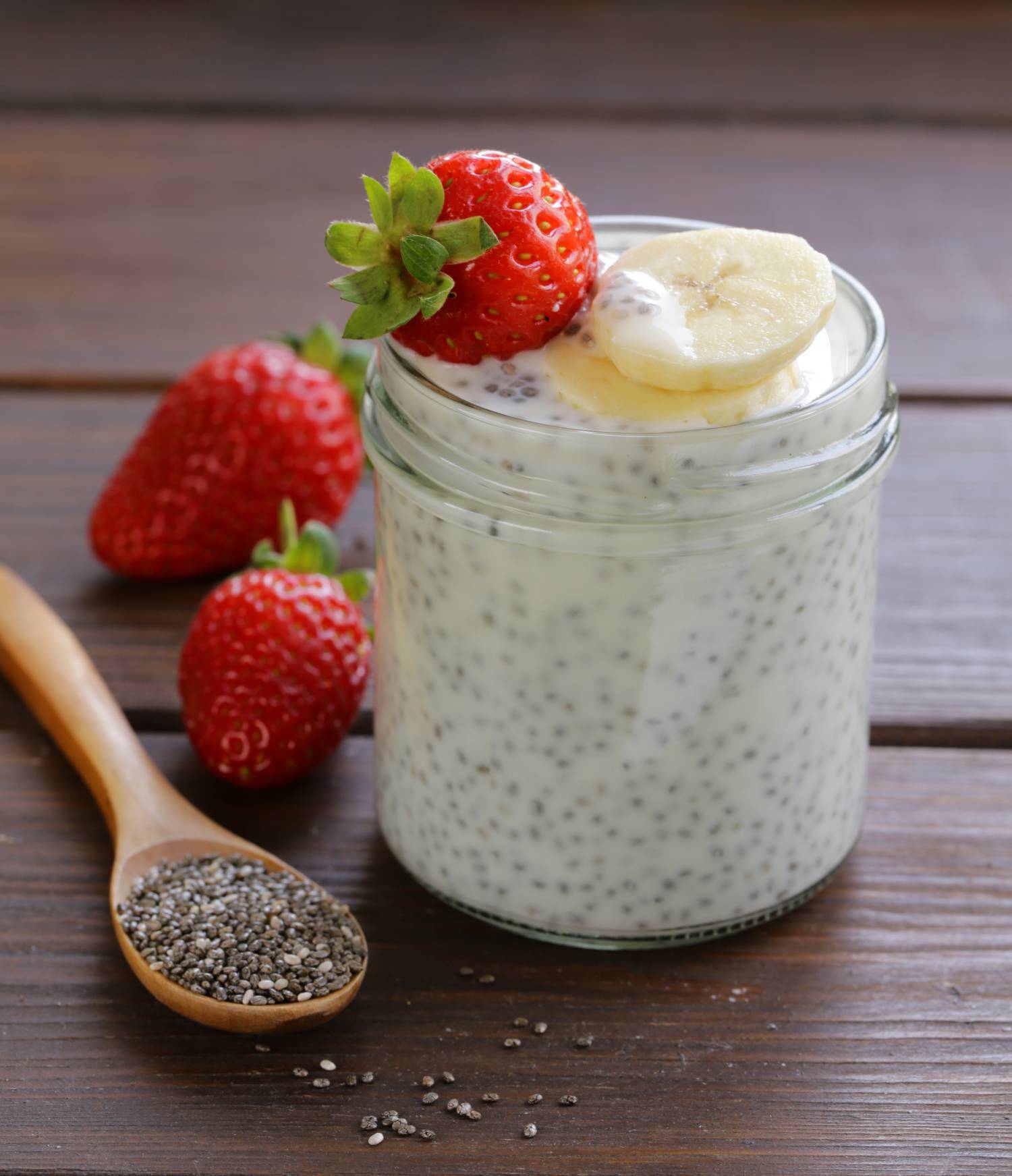 Yogurt and chia seed pudding in a jar with strawberries and bananas.