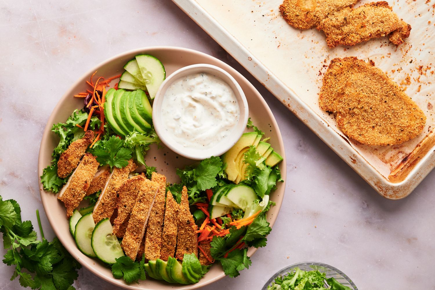 Baked chicken cutlets on a plate with salad and ranch dressing.