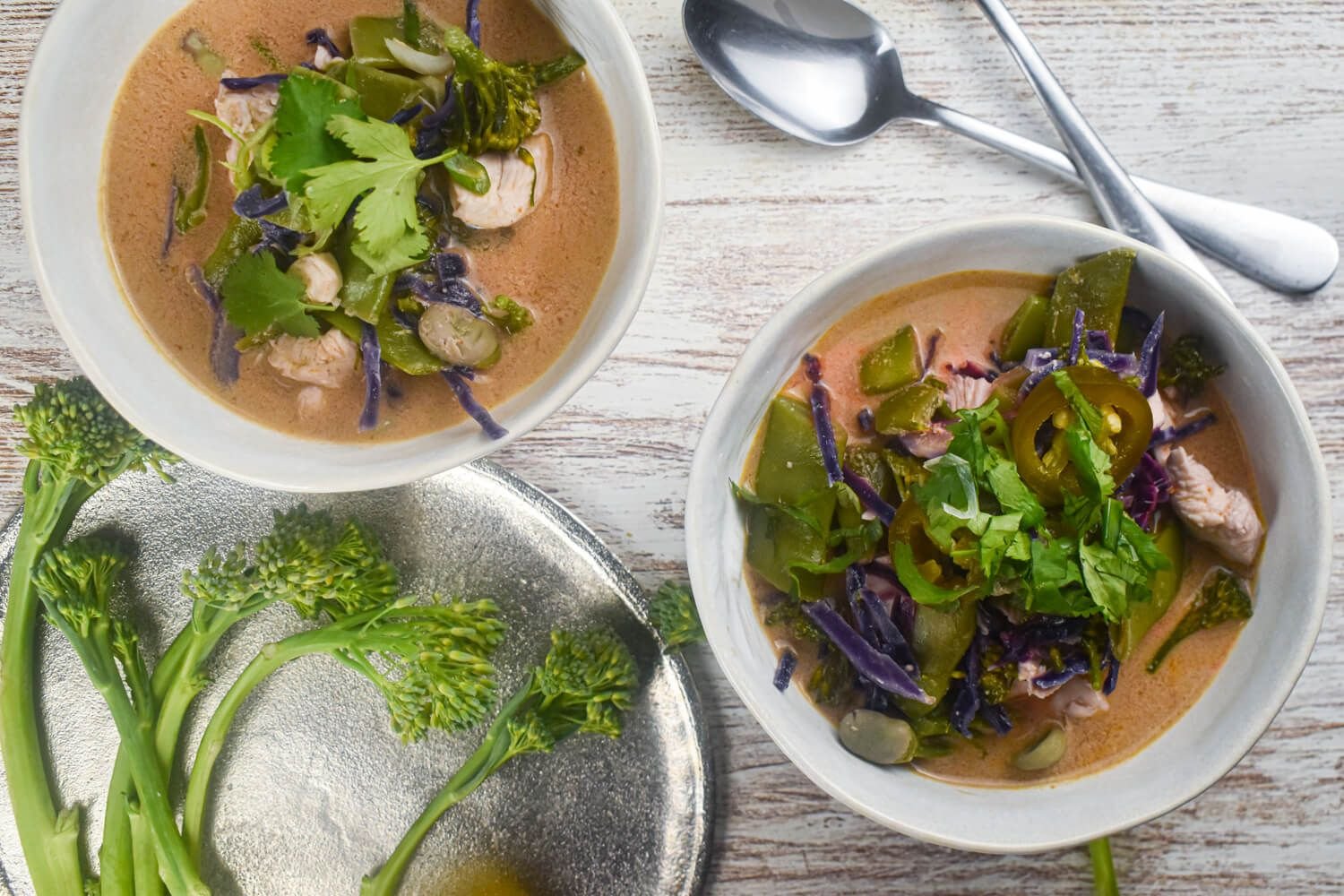 Chicken coconut curry soup with fresh vegetables, chicken breast, and red curry paste in a bowl.