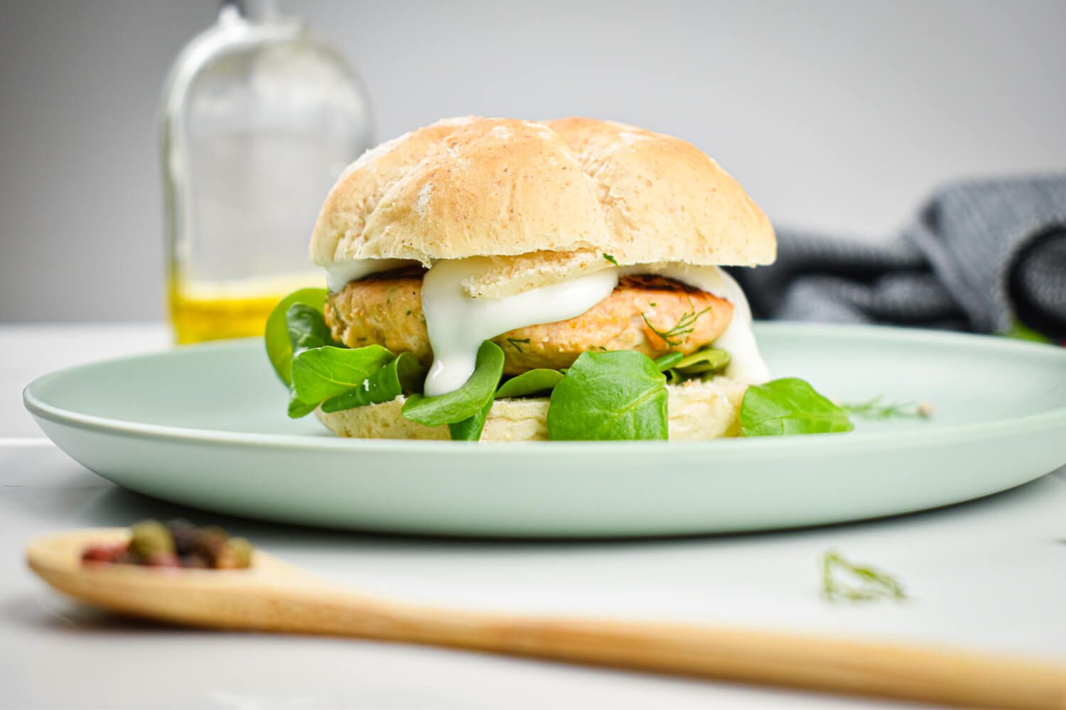 Dill Salmon Burgers with yogurt sauce and dressing on a whole wheat bun.