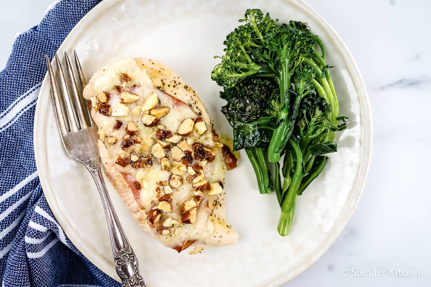 Chicken cordon bleu with ham and melted Swiss cheese on a plate with broccoli.