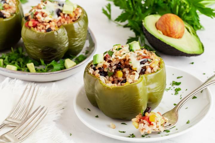 Slow cooker barbecue stuffed peppers with rice, beans, corn, onions, and diced avocado on a plate.