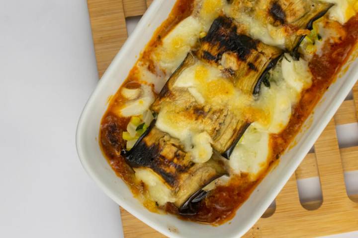 Baked eggplant rollatini with melted mozzarella cheese in a dish.