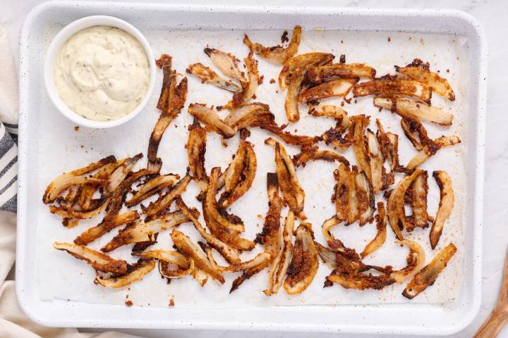 Baked onion straws with crispy browned edges on a baking sheet.